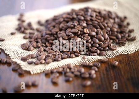 Geröstete Kaffeebohnen auf Leinwand alten hölzernen Hintergrund. Stockfoto