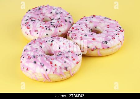 Drei frische bunte Donuts auf gelbem Hintergrund. Stockfoto