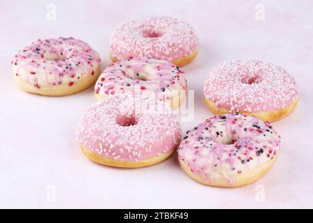 Viele bunte frische Donuts auf rosa Hintergrund. Stockfoto