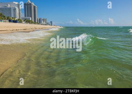 Wunderschöner Blick auf die hohen Gebäude entlang der Küste von Miami Beach, die sich mit der Wasserlinie verschmelzen und am Horizont in den blauen Himmel übergehen. Stockfoto