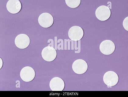 Wattepads auf lilafarbenem Hintergrund. Das Konzept der Reinigung, Hygiene, Medizin, Hautpflege, Make-up, umweltfreundliche Materialien Stockfoto