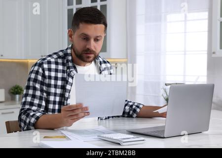 Mann, der Steuern am Tisch in der Küche macht Stockfoto
