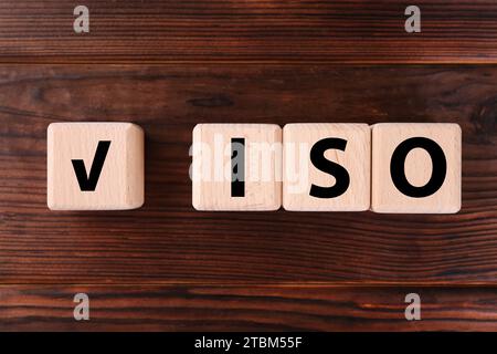 Würfel mit Häkchen und Abkürzung ISO auf Holztisch, flach gelegt Stockfoto