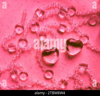 Transparente Herzen und Perlen auf Marmor in rosa Tönen. Perfekter Valentinstag Grußkarte Hintergrund Stockfoto