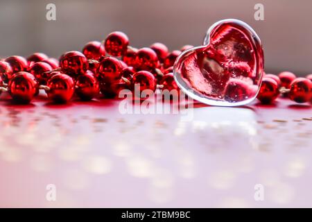 Glänzendes, transparentes Herz und rote Perlen. Perfekter Valentinstag Grußkarte Hintergrund Stockfoto