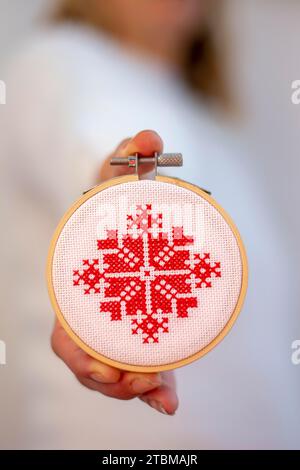 Frau mit handgemachtem Kreuzstich Folk Weihnachtsdekoration Stickerei auf Sperrholz. Nordische Schneeflocken Stockfoto