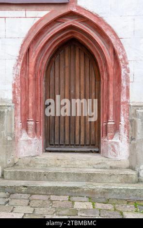 Eine bogenförmige alte alte Kirche, Holztür in einer Steinmauer Stockfoto