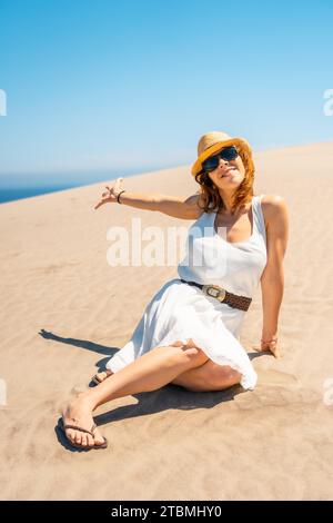 Vertikales Foto einer Frau, die eine idyllische Küstenlandschaft zeigt, die auf dem Sand in Cabo de Gata, Spanien, sitzt Stockfoto