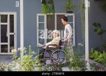 Ältere Frau entspannen sich im Rollstuhl im Hinterhof mit Tochter Stockfoto