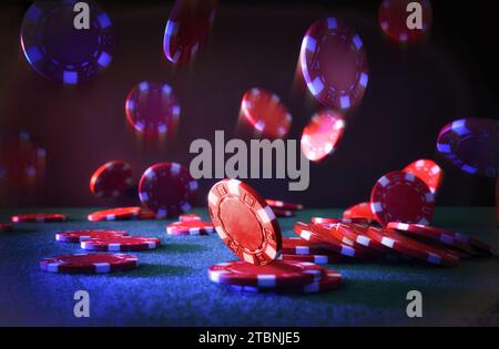 Rote Casino-Wetten-Chips fallen auf Filzmatte und dunkel isolierten Hintergrund. Vorderansicht. Stockfoto