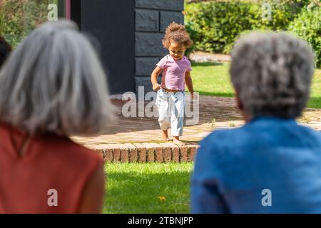 Herzzerreißende Szene von liebevollen Großeltern, die ihre junge Enkelin mit Zuneigung betrachten und einen zärtlichen Familienmoment im Freien festhalten. Stockfoto