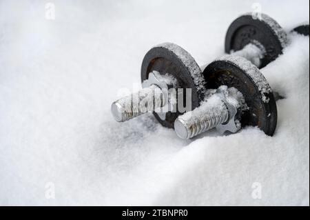 Sport im Winter Konzept. Kleine rostige Kurzhanteln, die von Schnee bedeckt sind. Verringerte Aktivität, Faulheit Stockfoto