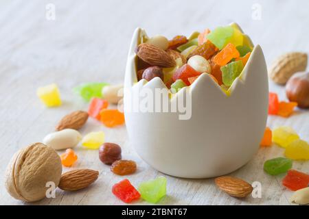 Mischung aus Nüssen und kandierten Früchten in einer eierförmigen Schüssel auf hellem Hintergrund, osterbackkonzept Stockfoto