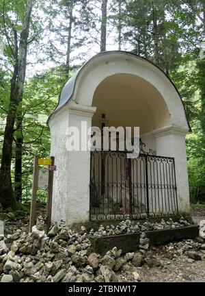 St. Gilgen, Österreich. 30. August 2023. Am steilen Weg nach Falkenstein am Wolfgangsee im Salzkammergut steht eine Kapelle mit einer Kreuzigungsgruppe am Kreuzweg Steine gegen Sünden, die auf die Wallfahrt zurückgeht. Das Salzkammergut ist Kulturhauptstadt 2024. Quelle: Beate Schleep/dpa/Alamy Live News Stockfoto