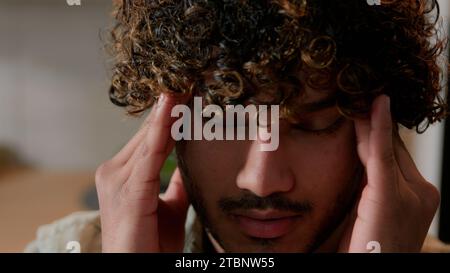 Nahaufnahme Kranke müde arabische männliche Massage Schläfen schmerzhafte Kopf Migräne Druck Kopfschmerz zu Hause Küche. Der Indianer leidet unter Kopfschmerzen. Ill Stockfoto