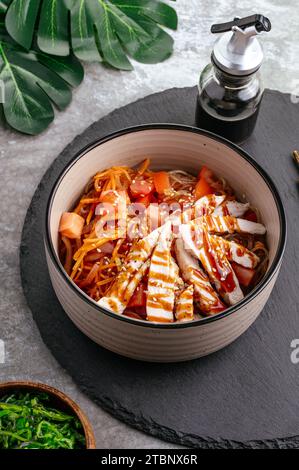 Asiatische Reisnudeln mit Gemüse, Sauce und Huhn in einer Schüssel Stockfoto