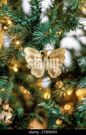 Nahaufnahme des goldenen Schmetterlings-Ornaments auf dem beleuchteten Weihnachtsbaum Stockfoto