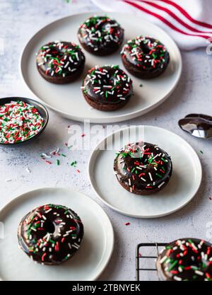 Nahaufnahme von Tellern mit Schokoladen-Donuts mit Weihnachtsstreuseln. Stockfoto