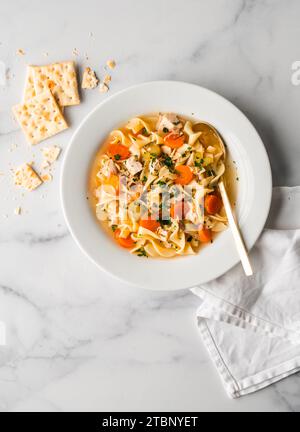 Eine Schüssel mit Hühnchennudelsuppe von oben auf weißem Marmor. Stockfoto