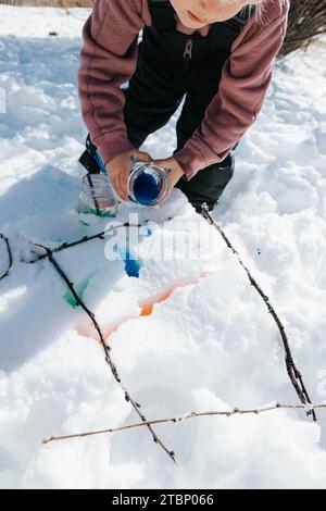 Mädchen malt Schnee mit Stöcken Stockfoto