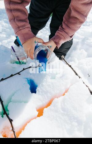 Mädchen malt Schnee mit Stöcken Stockfoto