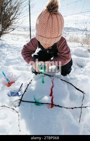 Mädchen malt Schnee mit Stöcken Stockfoto