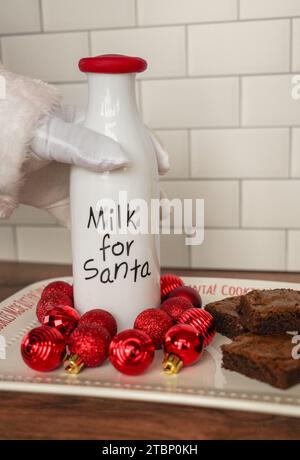 Der Weihnachtsmann greift nach Milch und Brownies in der Küche Stockfoto