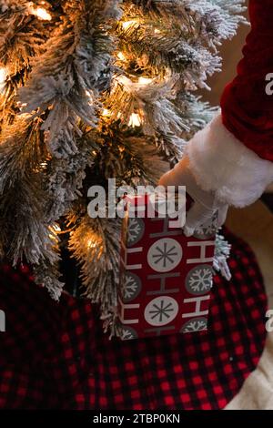 Der Weihnachtsmann hinterlässt ein Geschenk unter einem Weihnachtsbaum Stockfoto