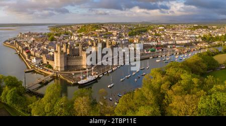 Aus der Vogelperspektive auf Caernarfon Castle und Stadt in herrlicher Abendsonne, Caernarfon, Wales, Großbritannien. Frühjahr (Mai) 2023. Stockfoto