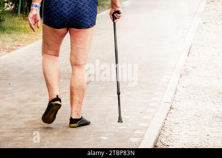 Schmerzen in den Beinen eines älteren Mannes, der entlang der Strandwege läuft. Pflege der Gelenkgesundheit. Stockfoto