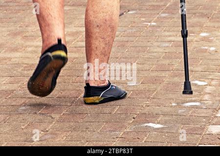 Schmerzen in den Beinen eines älteren Mannes, der entlang der Strandwege läuft. Pflege der Gelenkgesundheit. Stockfoto