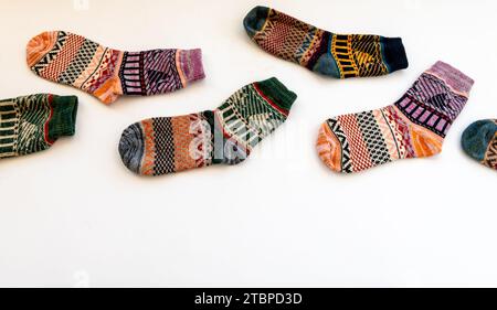 Farbenfrohe Wintersocken aus Wolle, die in einer gestaffelten Reihe in weiß angeordnet sind. Stockfoto