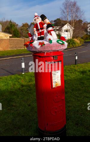 Poole, Dorset, Großbritannien. Dezember 2023. Ein gestrickter Briefkasten-Topper mit Weihnachtsmotiv erscheint auf einer roten Briefkiste und um die Laternenpfosten in Poole, Dorset. - Briefkastendeckel, Briefkastendeckel, Briefkastendeckel, Topper, Garnbombardierung, Garnbombe. Quelle: Carolyn Jenkins/Alamy Live News Stockfoto