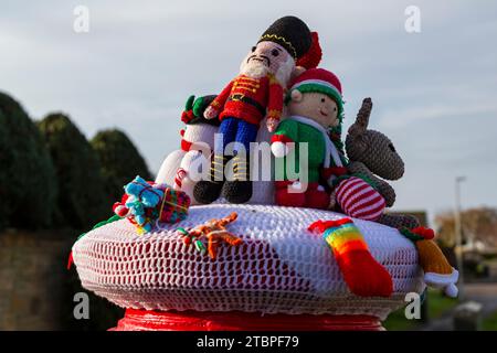 Poole, Dorset, Großbritannien. Dezember 2023. Ein gestrickter Briefkasten-Topper mit Weihnachtsmotiv erscheint auf einer roten Briefkiste und um die Laternenpfosten in Poole, Dorset. - Briefkastendeckel, Briefkastendeckel, Briefkastendeckel, Topper, Garnbombardierung, Garnbombe. Quelle: Carolyn Jenkins/Alamy Live News Stockfoto