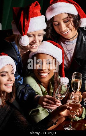 Überfreundete multiethnische Freundinnen in Sektgläsern und Weihnachtsfeiern in der Bar Stockfoto