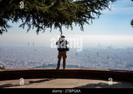 Ein erfahrener Fotograf, 70 Jahre alt, fängt Barcelonas Skyline von einem luftigen Aussichtspunkt ein und schafft ein zeitloses Bild des Panoramablicks der Stadt. Stockfoto