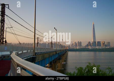 Wenn die Dämmerung über Seoul bricht, zieht sich die Jamsil Railroad Bridge über den Han River und schafft eine malerische Silhouette vor dem frühen Morgenhimmel. Stockfoto