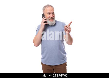Ein gutaussehender älterer Mann mit grauem Bart und Schnurrbart in einem T-Shirt spricht am Telefon Stockfoto