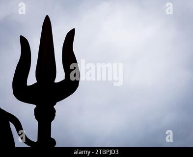 Hintergrundbeleuchtete Einzelaufnahme des hindu-Gottes shiva-Dreizacks mit dramatischem Hintergrund Stockfoto