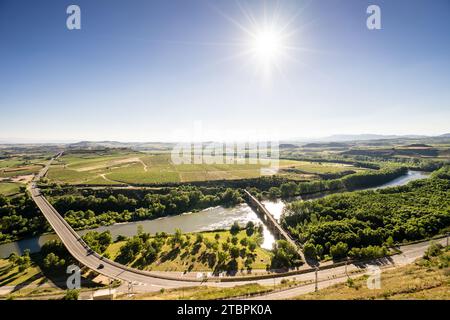 Ein atemberaubender Sonnenaufgang beleuchtet die weite Landschaft eines üppig grünen Tals, komplett mit einem sich windenden Fluss, der sich durch das Tal schlängelt Stockfoto