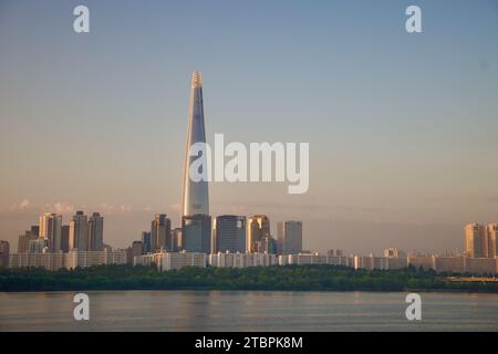 Der berühmte Lotte World Tower taucht in das Morgenlicht auf und dominiert die Skyline von Seoul. Diese majestätische Aussicht vom Ufer des Han Flusses fängt ein Stockfoto