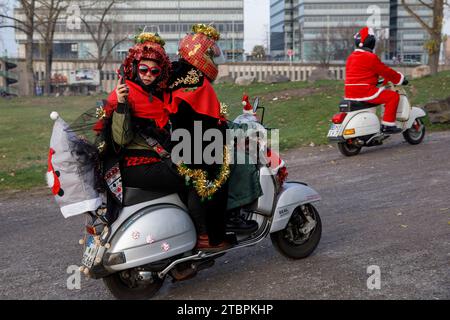 Mitglieder des Vespa-Rollervereins RheinSchalter Köln versammeln sich als Santas gekleidet auf der Deutzer Werft, bevor sie durch die Stadt fahren, zwei Frauen kleideten sich mit einem Stockfoto