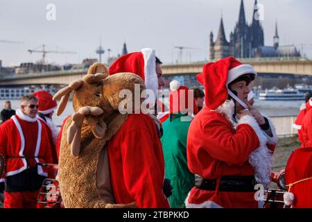 Mitglieder des Vespa-Rollervereins RheinSchalter Köln, verkleidet als Santas, versammeln sich auf der Deutzer Werft, bevor sie eine Fahrt durch die Stadt machen, santa mit gefülltem Rei Stockfoto