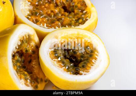 Nahaufnahme einer frisch geernteten Passionsfrucht, die in zwei Hälften geschnitten ist und ihr saftiges gelbes und rotes Fruchtfleisch offenbart Stockfoto