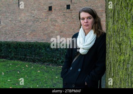 Breda, Niederlande. Porträt einer mittelerwachsenen kaukasischen Frau, die sich an den Baum eines Stadtparks lehnt. Stockfoto