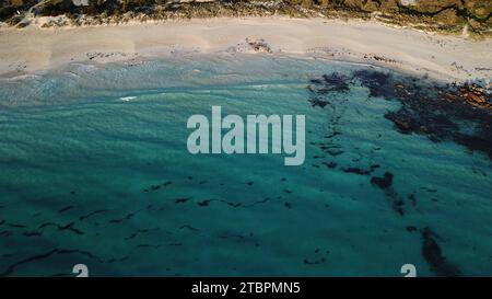 Ein Blick aus der Vogelperspektive auf einen abgeschiedenen Sandstrand, umgeben von einer felsigen Küste Stockfoto