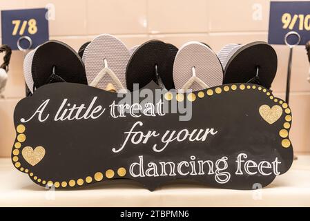 Ein Schild mit der Aufschrift „Ein kleiner Leckerbissen für Ihre tanzenden Füße“ vor einem Eimer Sandalen Stockfoto