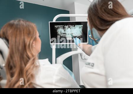 Der Zahnarzt analysiert sorgfältig das MRT-Bild der Mundhöhle, um die Behandlung zu planen. Der Patient erhält eine individuelle Konsultation von einem Stockfoto