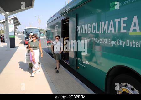 (231208) -- DUBAI, 8. Dezember 2023 (Xinhua) -- Menschen steigen an einer Haltestelle für die UN-Klimakonferenz in Dubai, den Vereinigten Arabischen Emiraten (VAE), aus einem internen Shuttle, der von King Long, einem der führenden chinesischen Bushersteller, bedient wird 2023. Die Busse, die für die laufende COP28-Klimakonferenz bestimmt sind, sind mit hellen Farben, hauptsächlich blau oder grün, gestrichen, um das Umweltbewusstsein zu fördern. Einige dieser Busse sind reine Elektrofahrzeuge aus China. Neben Higer auch Elektrobusse anderer chinesischer Autohersteller wie Yutong und Stockfoto