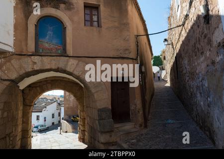 Gasse und Arco del Cristo mit gemaltem Kruzifix hinter Glas darüber. Einer der Eingänge der Altstadt von Caceres, Extremadura, Spanien Stockfoto